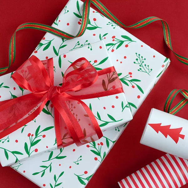 2 boxes wrapped in a green/red holly design, stacked and wrapped with a red ribbon. 