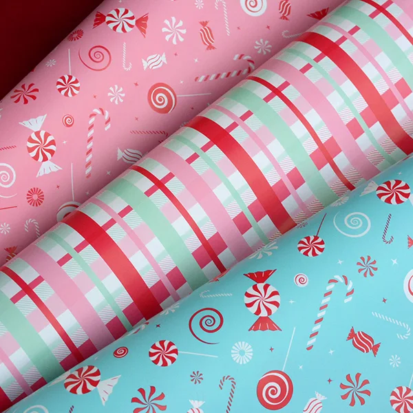 3 wrapping paper designs fanned out to show a candy cane design in pink/red and turquoise/red and also a check design in pink, mint and red.