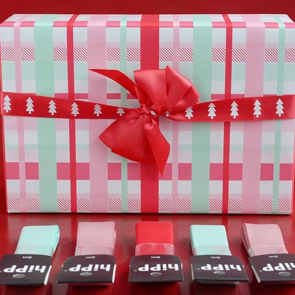 A box wrapped in a check design with pink, red and mint colours. Also featured are ribbon hangsells in colours matching the paper.